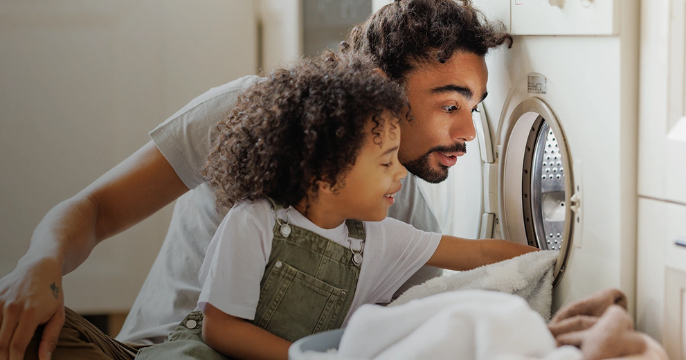 Father and daughter getting laundry out of the washing machine