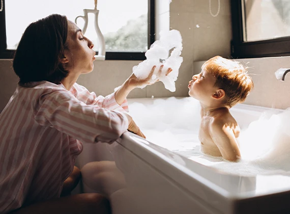 Mother bathing her baby in a bath tub with soft water