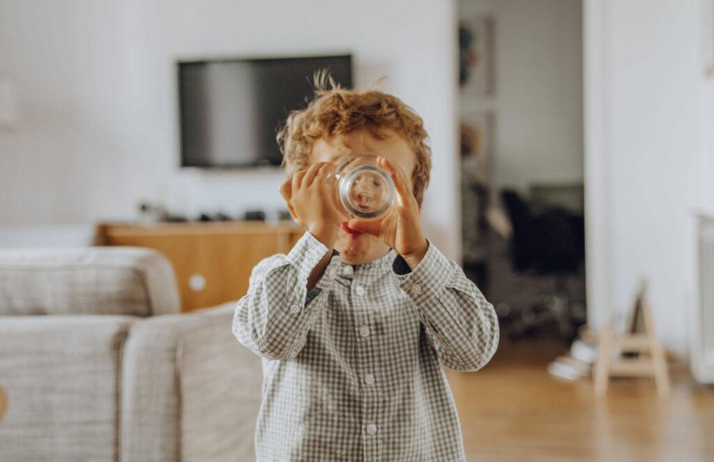 A young boy drinking water our of a glass