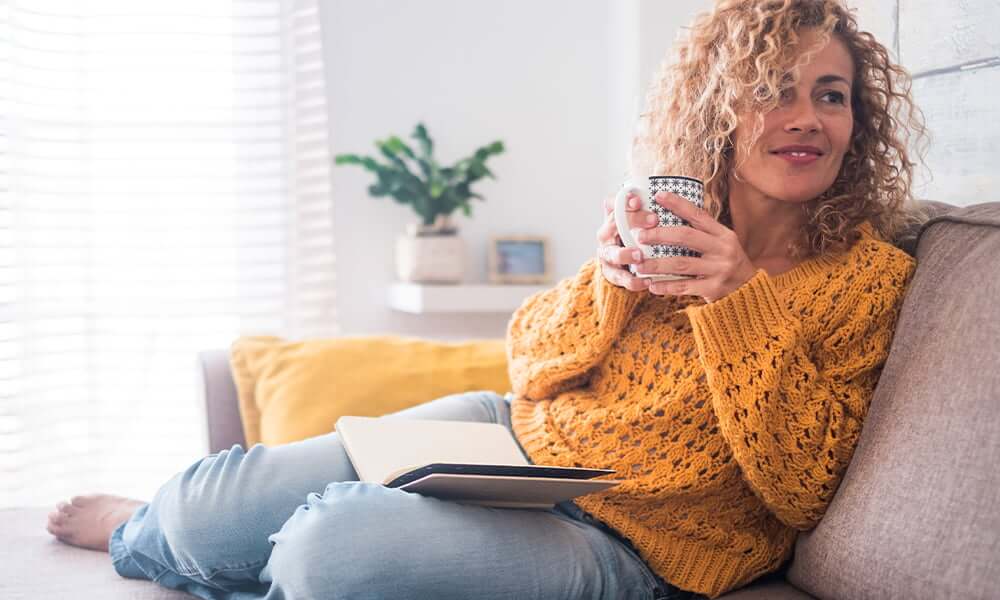 lady sat on sofa holding a mug