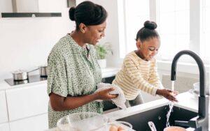 mother and child in a kitchen by a sink