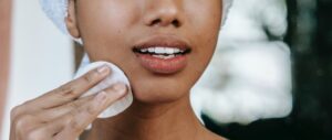 A woman wiping her face with a cotton pad